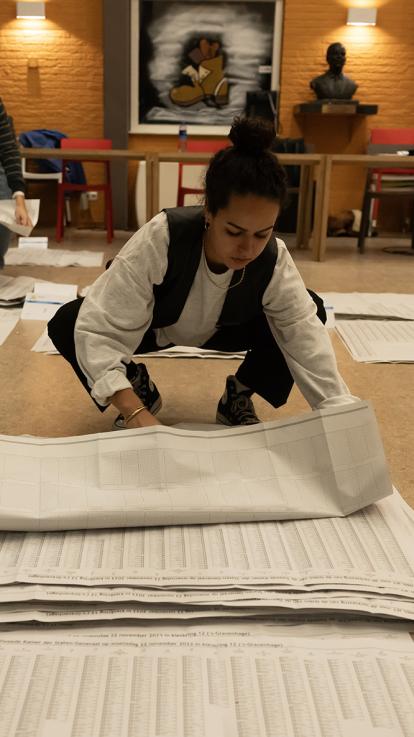 Vrijwilliger (vrouw) vouwt stemformulieren op