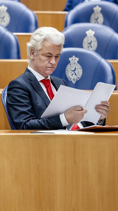 Wilders bekijkt papieren zittend in de Tweede Kamer