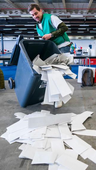 een teller gooit de stembiljetten uit de stemcontainer