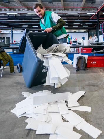 een teller gooit de stembiljetten uit de stemcontainer