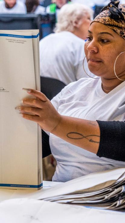 een vrijwilliger sorteert stembiljetten