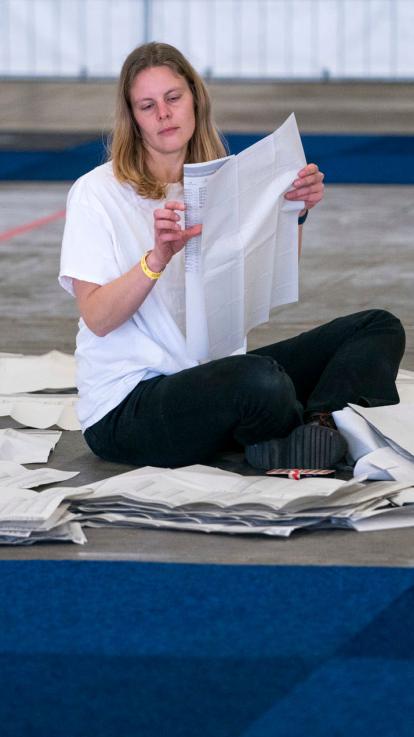 een vrijwilliger zit op de grond stemmen te tellen