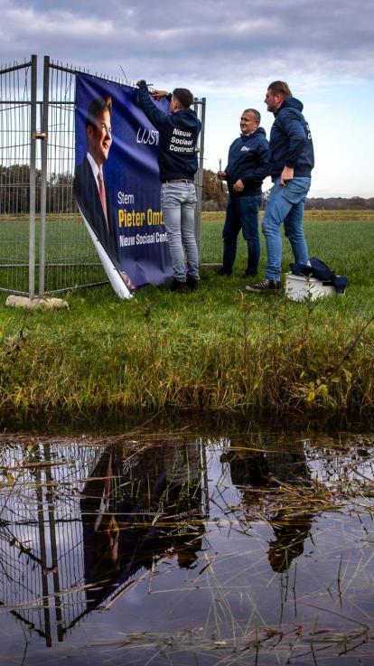 partijleden hangen een verkiezingsposter op voor NSC 