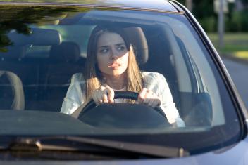 Vrouw kijkt geschokt terwijl ze achter het stuur zit in de auto
