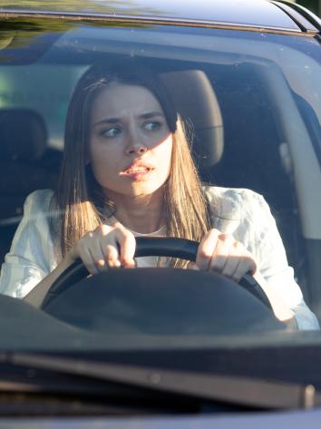 Vrouw kijkt geschokt terwijl ze achter het stuur zit in de auto
