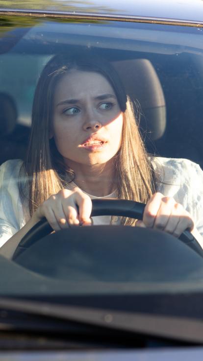 Vrouw kijkt geschokt terwijl ze achter het stuur zit in de auto