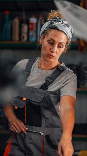 een vrouw werkt in een autogarage en wijst iets aan