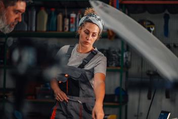 een vrouw werkt in een autogarage en wijst iets aan