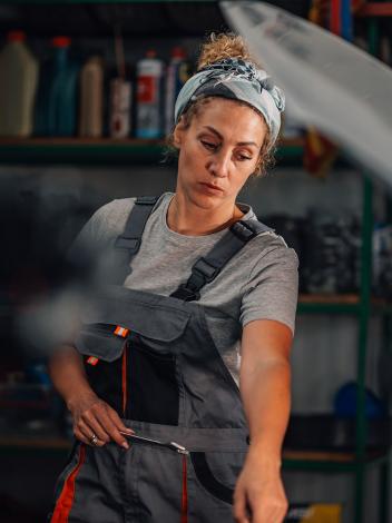 een vrouw werkt in een autogarage en wijst iets aan