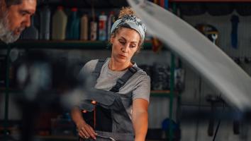 een vrouw werkt in een autogarage en wijst iets aan