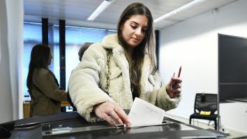 Jonge vrouw doet haar stembiljet in een kliko
