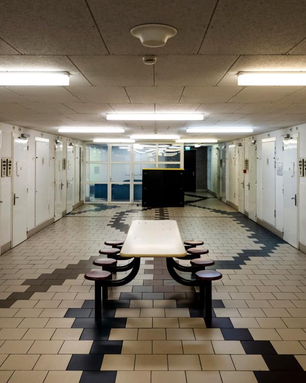 Interieur van een detentiecentrum met deuren en een tafel met krukjes