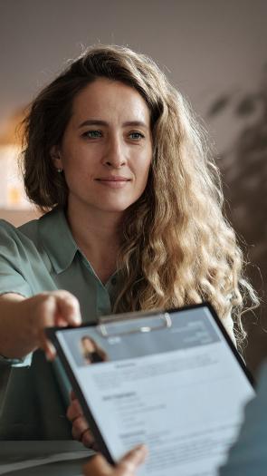 iemand geeft een cv aan bij een sollicitatiegesprek