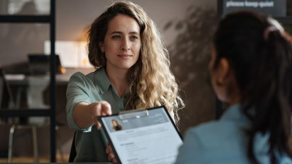 iemand geeft een cv aan bij een sollicitatiegesprek