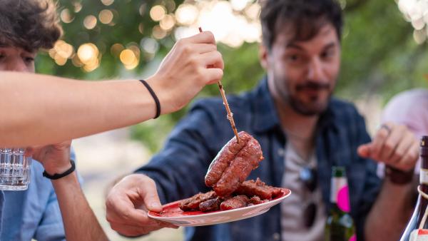 mensen pakken rauw vlees van een bordje voor de bbq