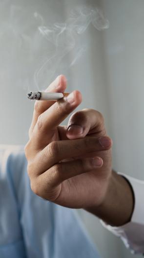 sigaret in iemands hand, iemand anders doet op de achtergrond een hand voor z'n mond