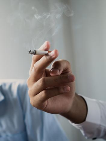 sigaret in iemands hand, iemand anders doet op de achtergrond een hand voor z'n mond