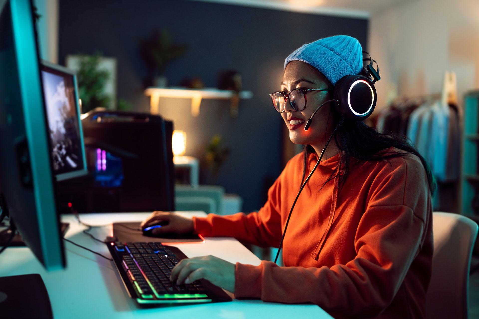 Vrouw zit achter een computer videogames te spelen.