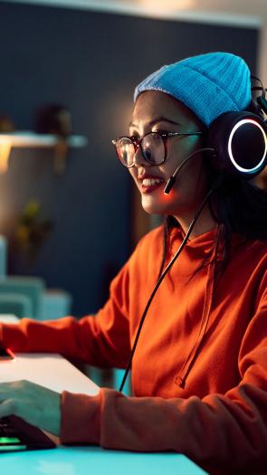 Vrouw zit achter een computer videogames te spelen.