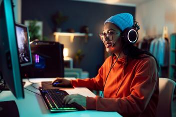 Vrouw zit achter een computer videogames te spelen.