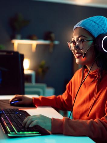 Vrouw zit achter een computer videogames te spelen.