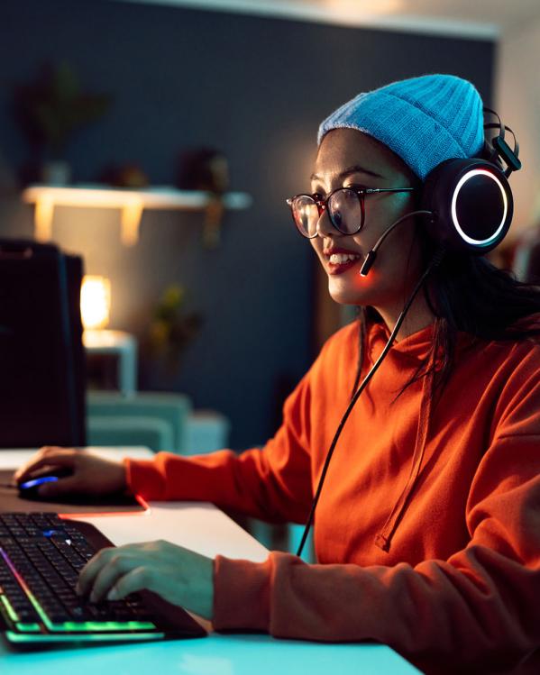 Vrouw zit achter een computer videogames te spelen.