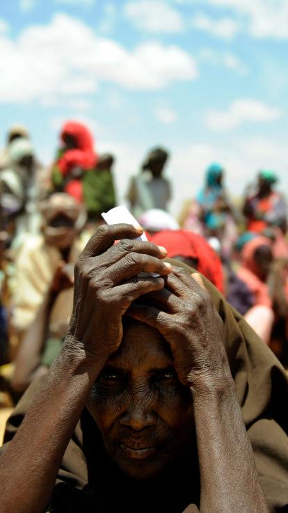 een wachtende kijkt triest voor zich uit met andere mensen wachtend op de achtergrond