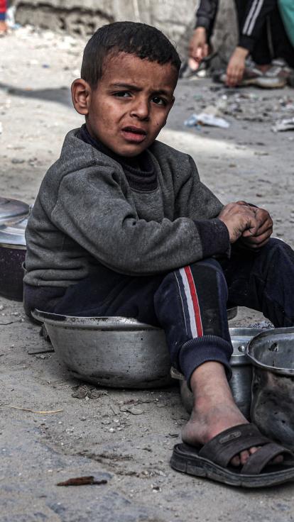 jongens in Gaza zitten te wachten om hun lege pannen te vullen met voedsel
