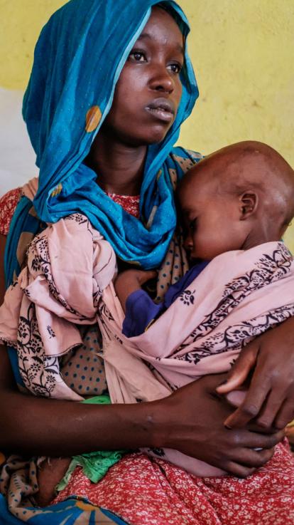 een moeder houdt haar ondervoede kind vast