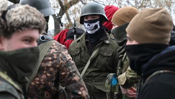 Jongen draagt een oud Duits legeruniform met stahlhelm en gezichtsbedekking met een schedel erop.