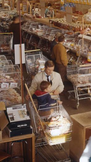 Vader met zoon in winkelwagen in supermarkt 