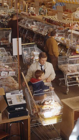 Vader met zoon in winkelwagen in supermarkt 