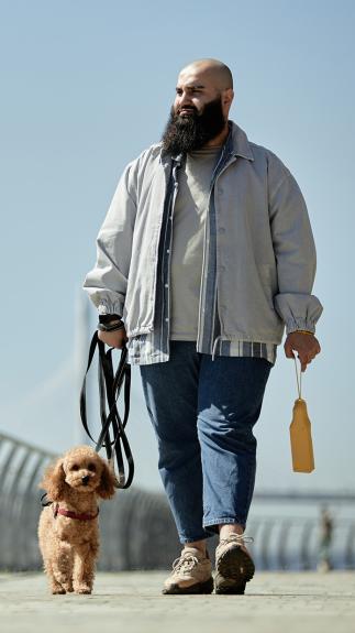een man laat de hond uit vlakbij het strand