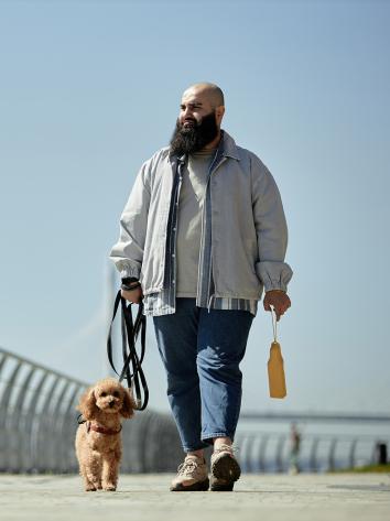 een man laat de hond uit vlakbij het strand