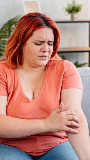 een vrouw zit aan huiduitslag op haar arm