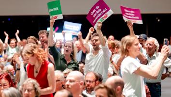 leden van GroenLinks-PvdA houden bordjes omhoog tijdens het ledencongres