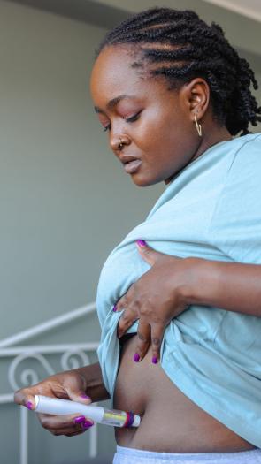 een vrouw injecteert zichzelf in de buik met hormonen 