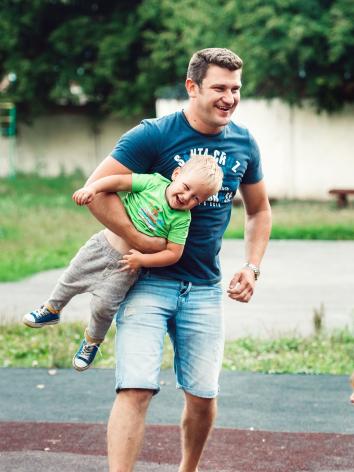 een vader speelt buiten met zijn kinderen