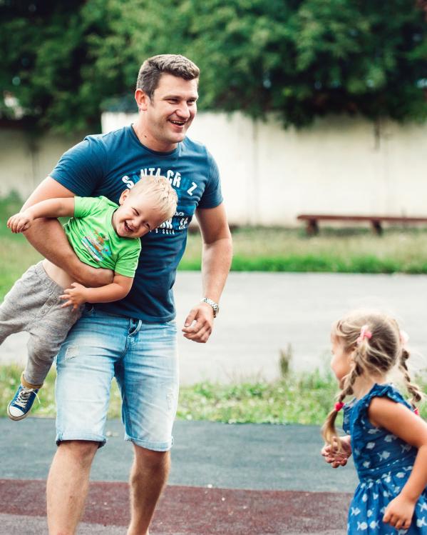 een vader speelt buiten met zijn kinderen