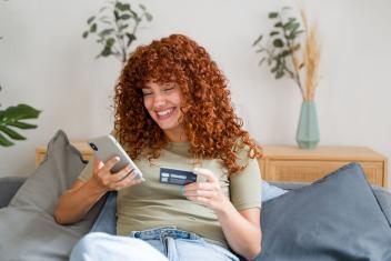 Een vrouw zit vrolijk online te shoppen.