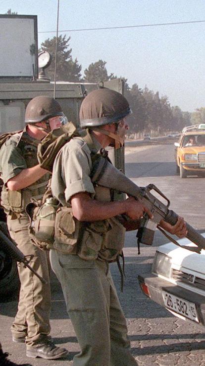 Israëlische militairen lopen met wapens over straat in Gaza in 1998