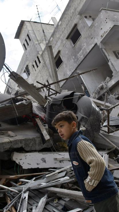 Jonge jongen staat tussen het puin van flatgebouwen