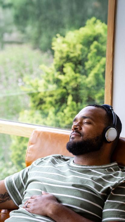 Een man die ontspannen in een stoel muziek luistert 