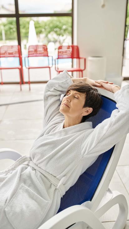 Een vrouw die in haar badjas op een zwembadbed ligt 