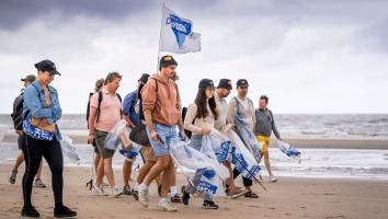 vrijwilligers met prikkers en afvalzakken op het strand