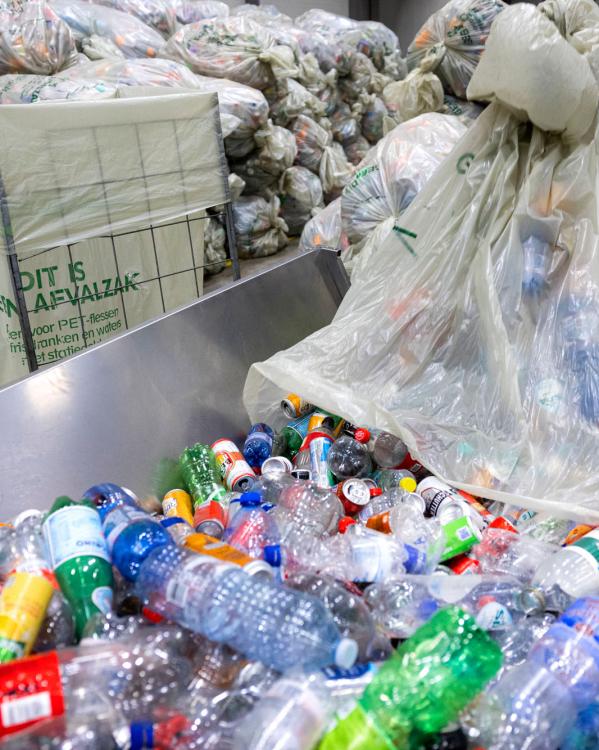 ingezamelde plastic flessen en blikjes op een loopband