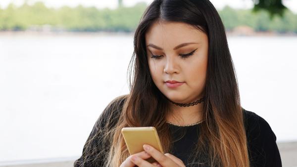 een meisje achter haar telefoon