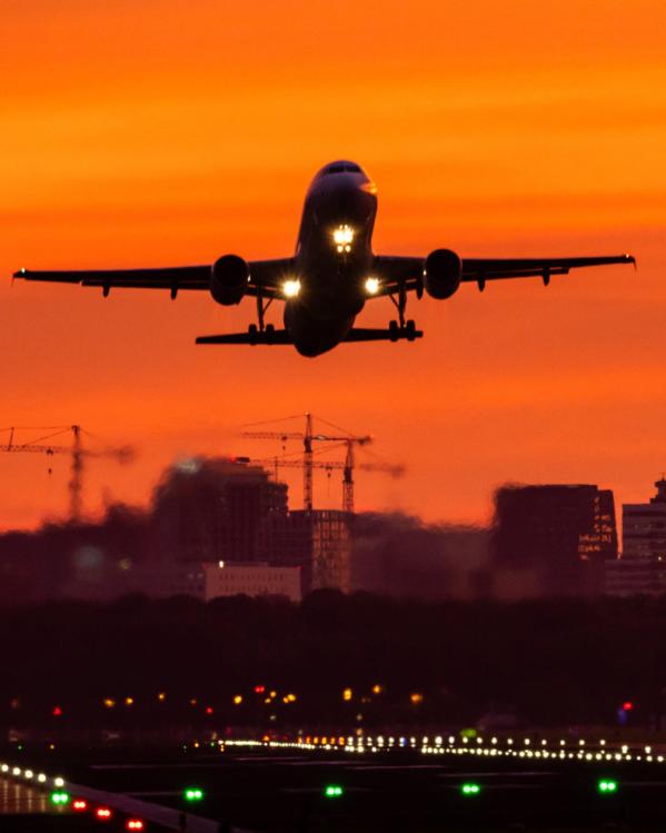 Een vliegtuig stijgt op bij zonsondergang