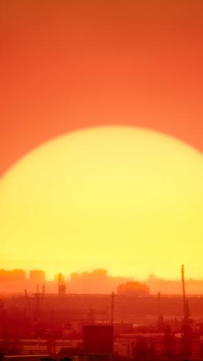 een ondergaande zon achter een industriegebied