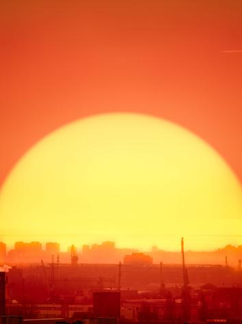 een ondergaande zon achter een industriegebied